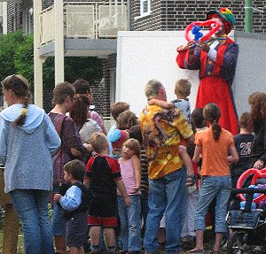 Ballonknstler als Clown auf Stelzen modelliert Luftballons am Stadtfest