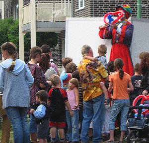 Ballonk�nstler als Clown auf Stelzen modelliert Luftballons am Stadtfest
